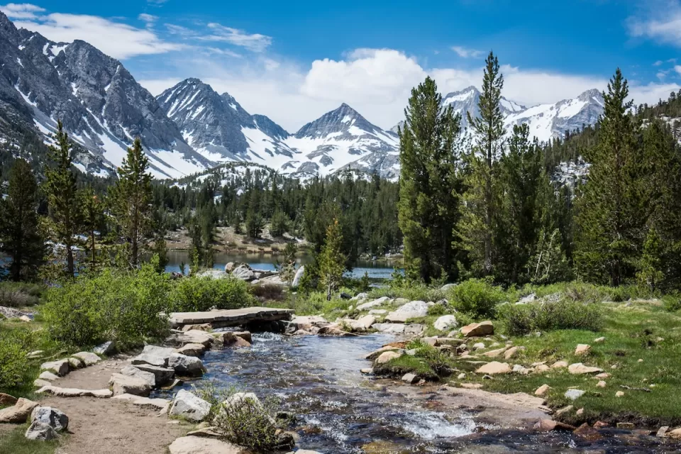 Small mountain lake with snow-capped mountains in background in Eastern Sierra Nevada mountains in California.